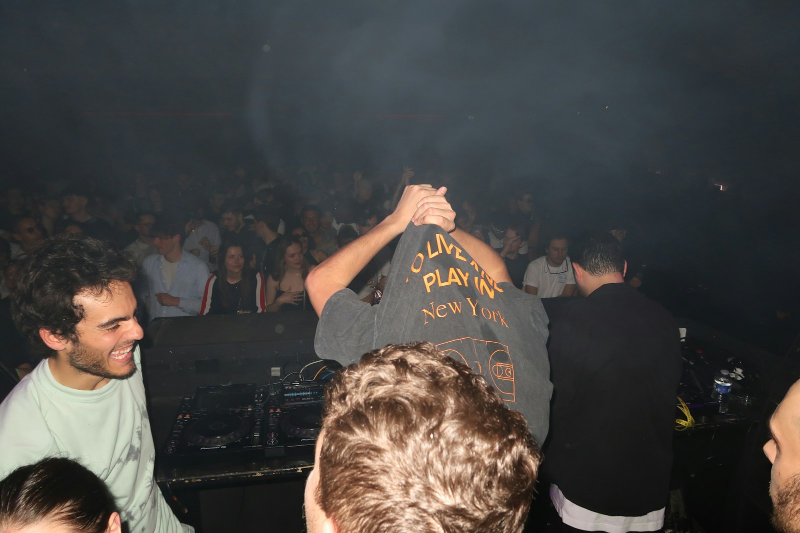 A crowd enjoys a concert in a dark venue.