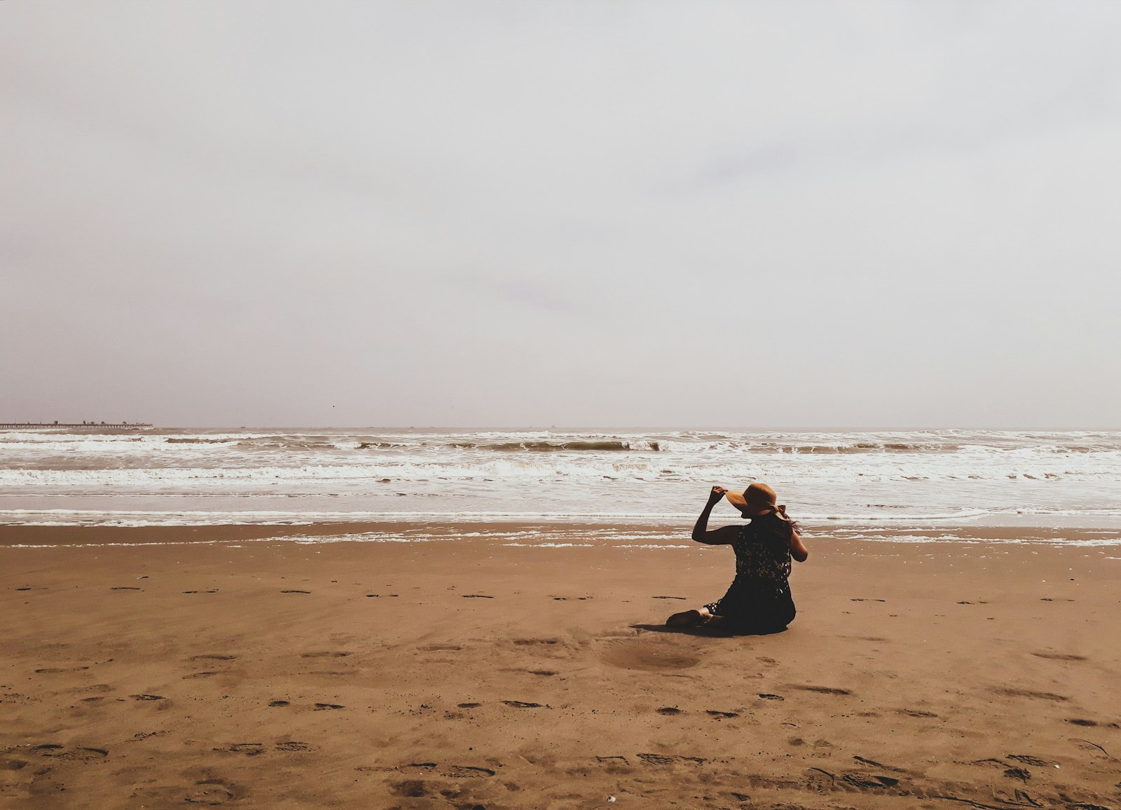 a woman sitting on a beach looking at the ocean